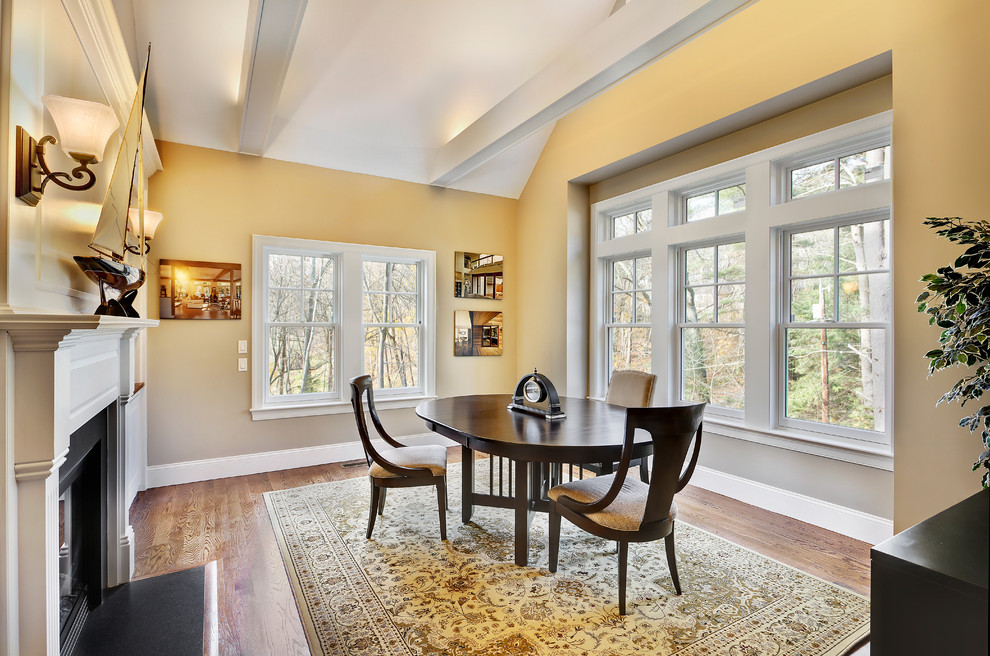 Classic study in Boston with beige walls, medium hardwood flooring, a standard fireplace, a plastered fireplace surround and a freestanding desk.