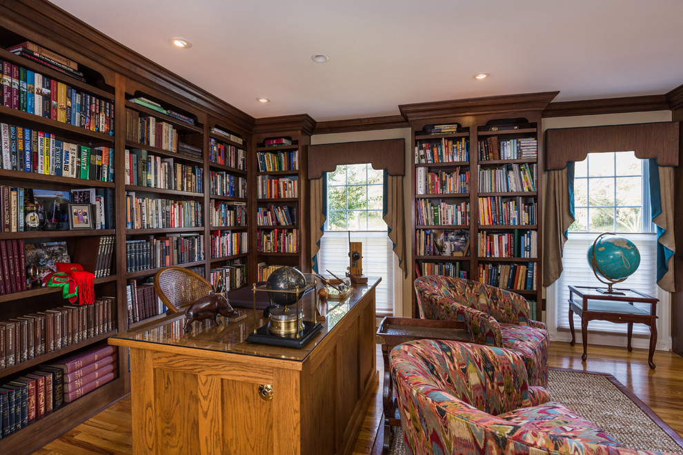 Esempio di un grande studio tradizionale con libreria, pareti beige, pavimento in legno massello medio, scrivania incassata e pavimento marrone