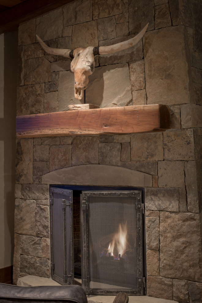 Example of a mountain style study room design in Denver with a two-sided fireplace and a stone fireplace