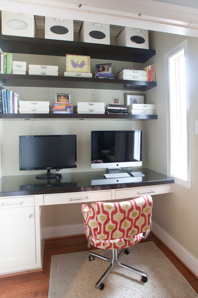 Modelo de despacho actual de tamaño medio sin chimenea con paredes beige, suelo de madera en tonos medios, escritorio empotrado y suelo marrón