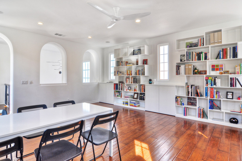 Foto di un ampio atelier minimalista con pareti bianche, pavimento in legno massello medio, nessun camino e scrivania autoportante