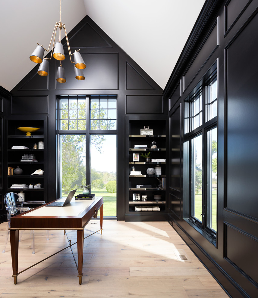 Diseño de despacho minimalista de tamaño medio sin chimenea con biblioteca, paredes negras, suelo de madera clara, escritorio independiente y suelo beige