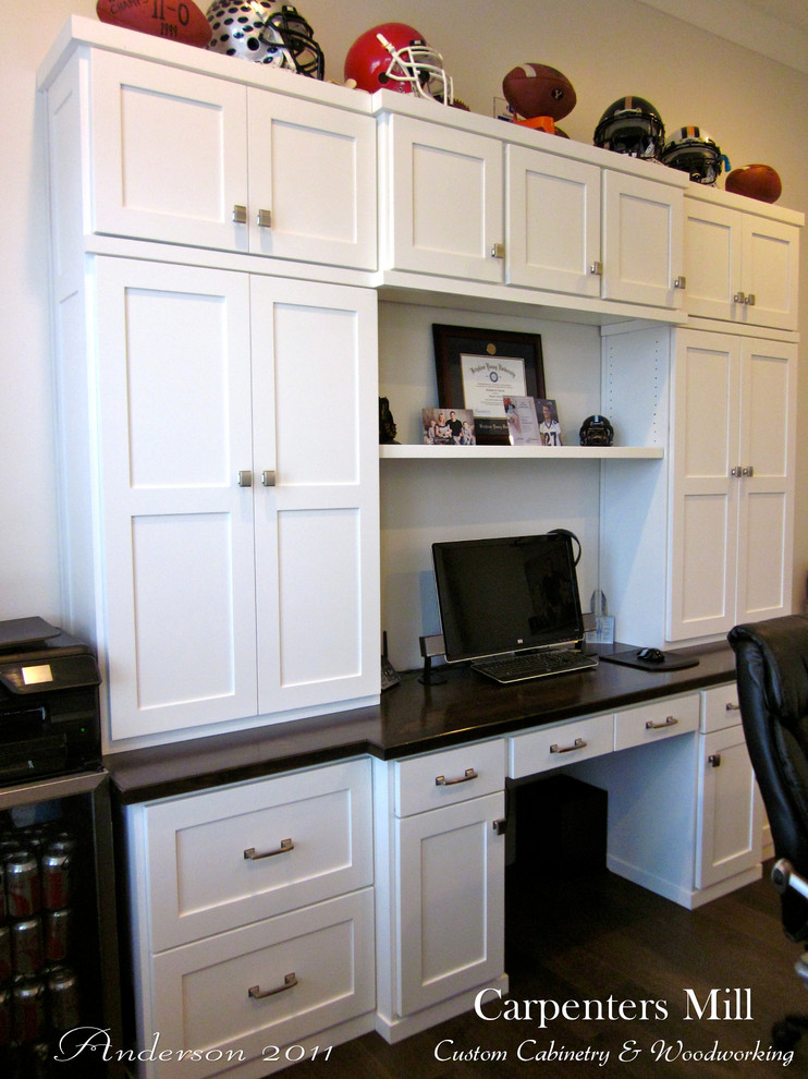 Ejemplo de despacho de estilo americano sin chimenea con escritorio empotrado, paredes grises y suelo de madera oscura