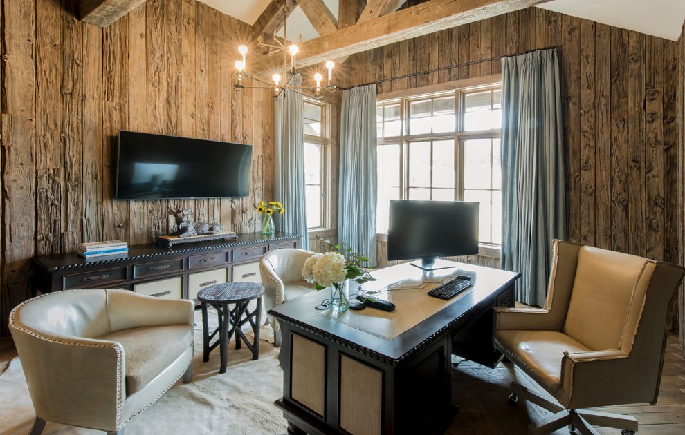 Modelo de despacho de estilo de casa de campo grande con paredes marrones, suelo de madera clara y escritorio independiente