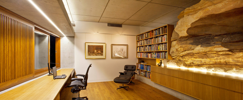 Diseño de despacho contemporáneo de tamaño medio con paredes blancas, suelo de madera en tonos medios y escritorio empotrado