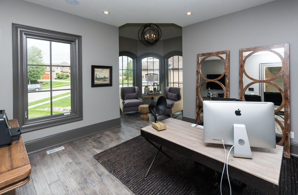 Modernes Arbeitszimmer ohne Kamin mit Arbeitsplatz, beiger Wandfarbe, freistehendem Schreibtisch und braunem Holzboden in Sonstige