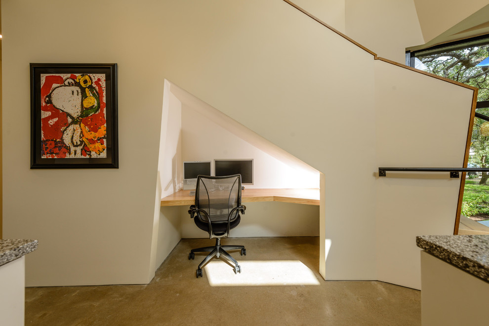 Small trendy built-in desk concrete floor study room photo in Austin with white walls and no fireplace