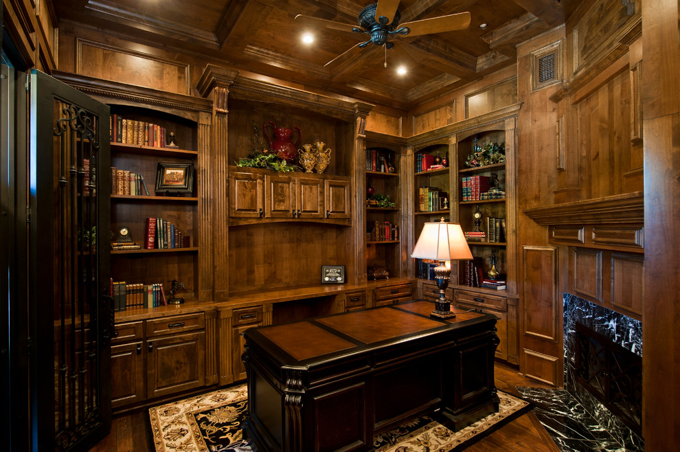 Geräumiges Mediterranes Arbeitszimmer mit Arbeitsplatz, brauner Wandfarbe, hellem Holzboden, Kamin und freistehendem Schreibtisch in Austin