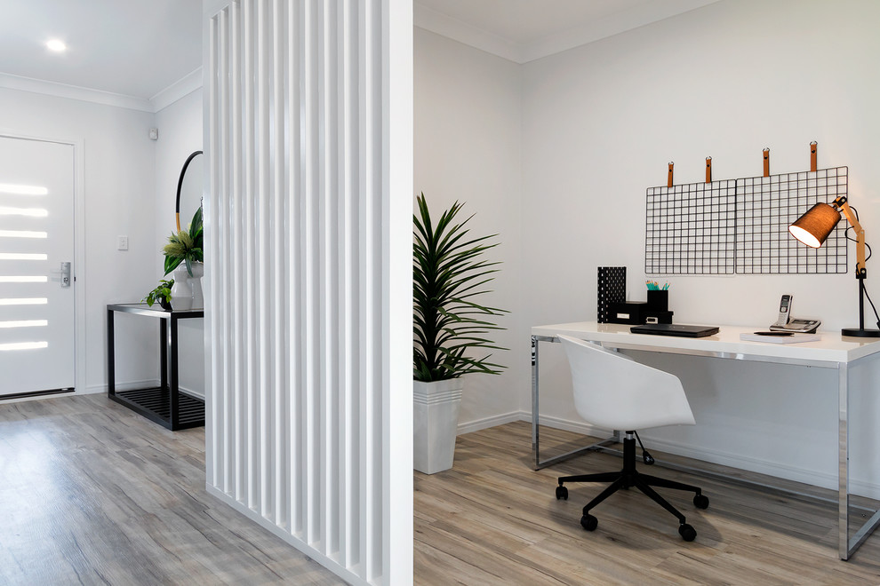 На фото: кабинет в современном стиле с белыми стенами, отдельно стоящим рабочим столом и коричневым полом