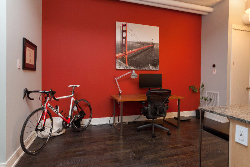 Ejemplo de despacho minimalista pequeño sin chimenea con paredes rojas, suelo de madera oscura, escritorio independiente y suelo marrón