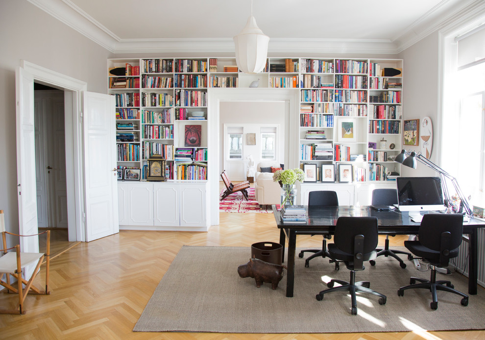 Cette photo montre un grand bureau chic avec un mur gris, parquet clair, une bibliothèque ou un coin lecture, un bureau indépendant, un sol marron, une cheminée d'angle et un manteau de cheminée en bois.