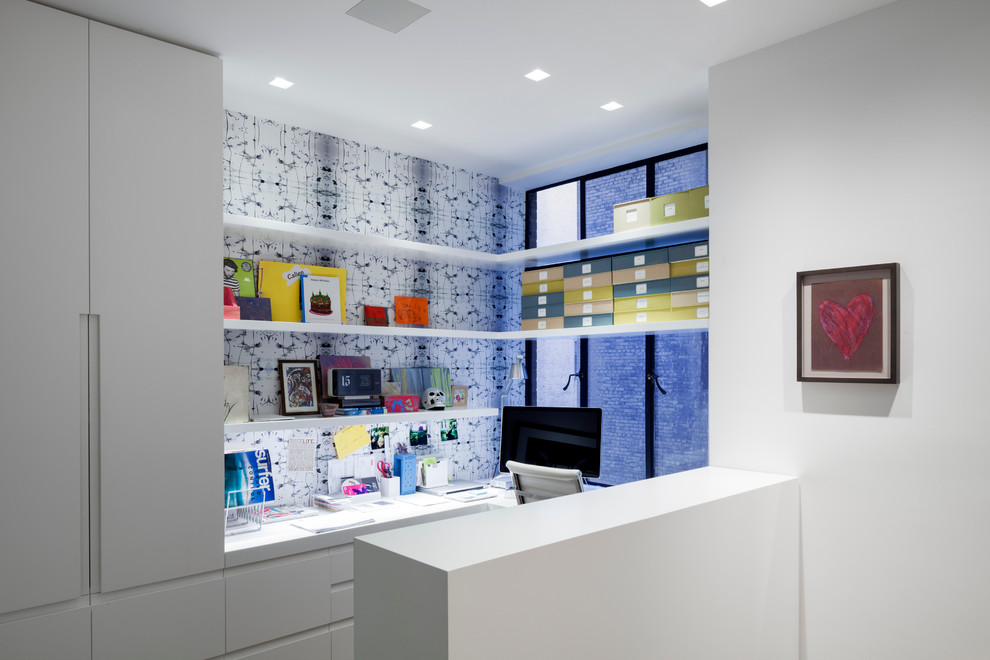 This is an example of a small contemporary home office in New York with white walls and a built-in desk.