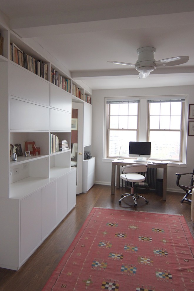 Esempio di un piccolo studio contemporaneo con libreria, pareti bianche, pavimento in legno massello medio, scrivania autoportante e pavimento marrone