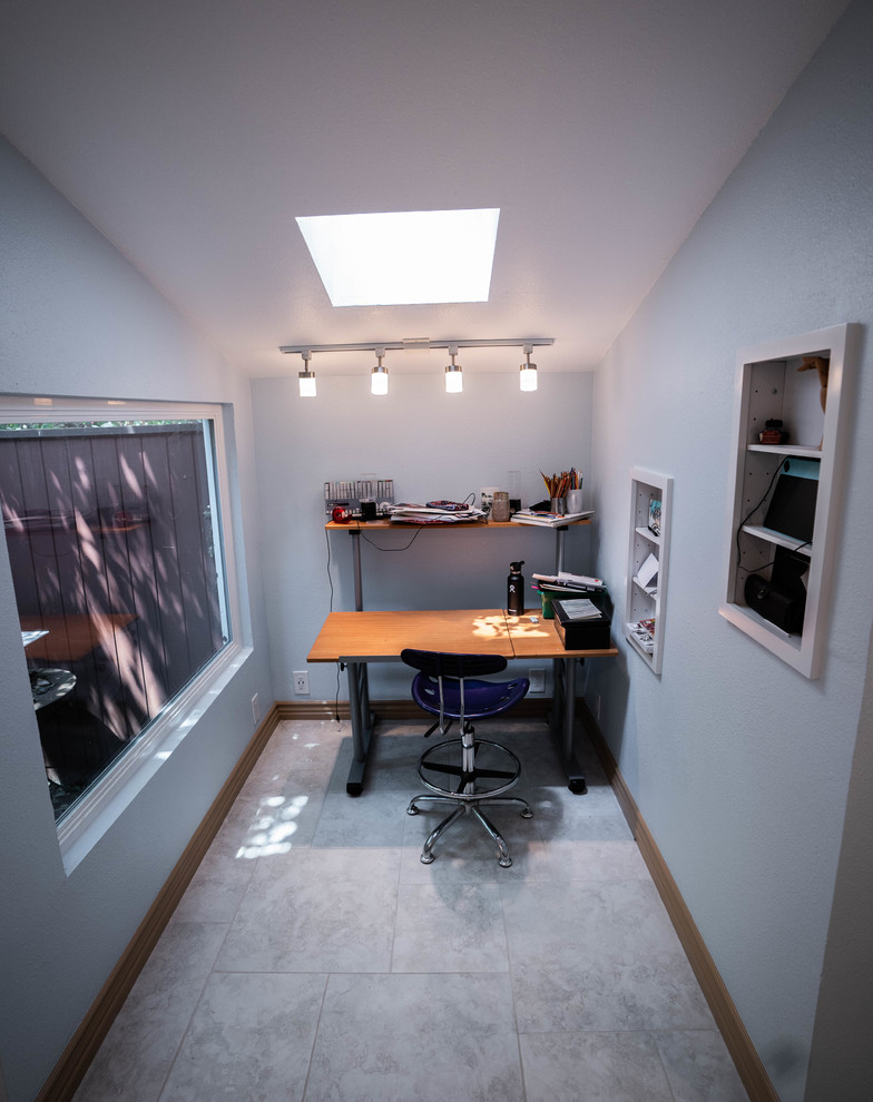 Modelo de sala de manualidades minimalista grande sin chimenea con paredes azules, suelo de pizarra, escritorio empotrado y suelo gris