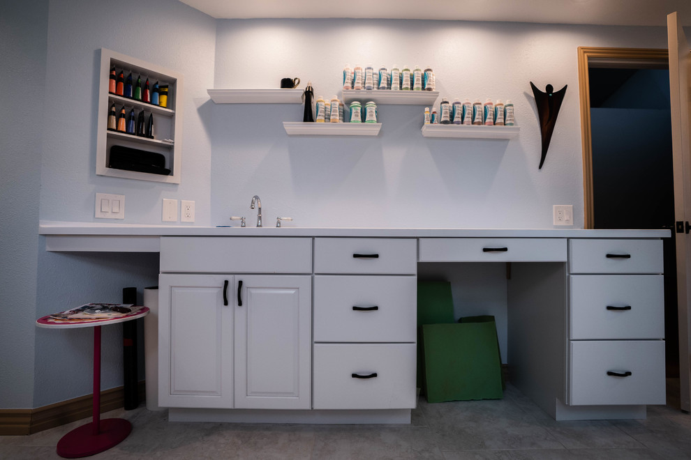 Imagen de sala de manualidades minimalista grande sin chimenea con paredes azules, escritorio empotrado, suelo de pizarra y suelo gris