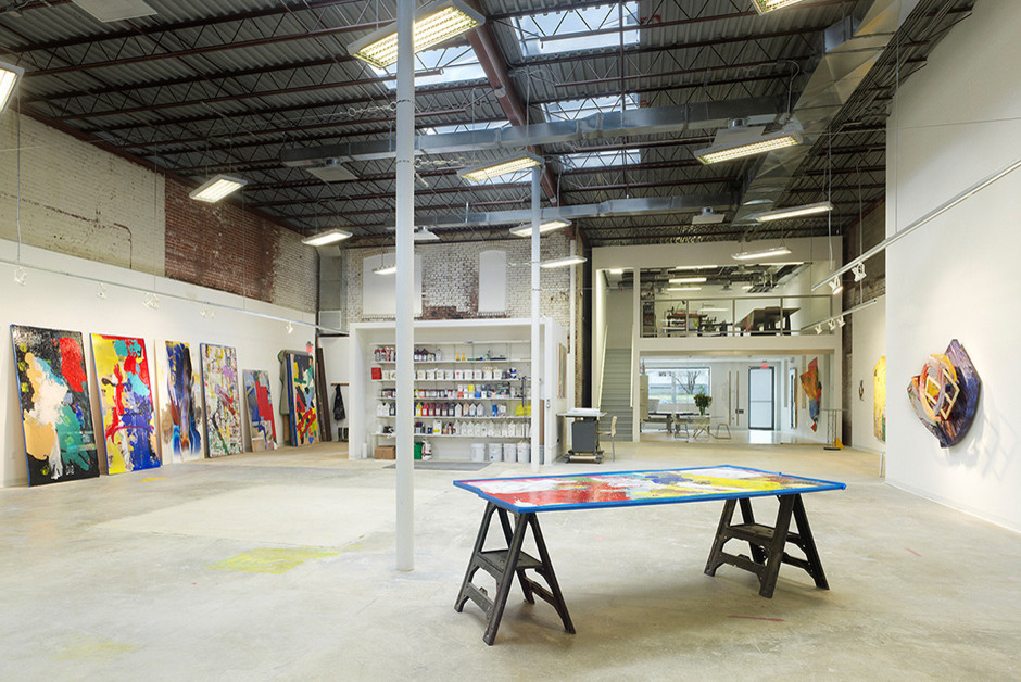 Großes Industrial Arbeitszimmer mit Studio, weißer Wandfarbe und hellem Holzboden in Charlotte