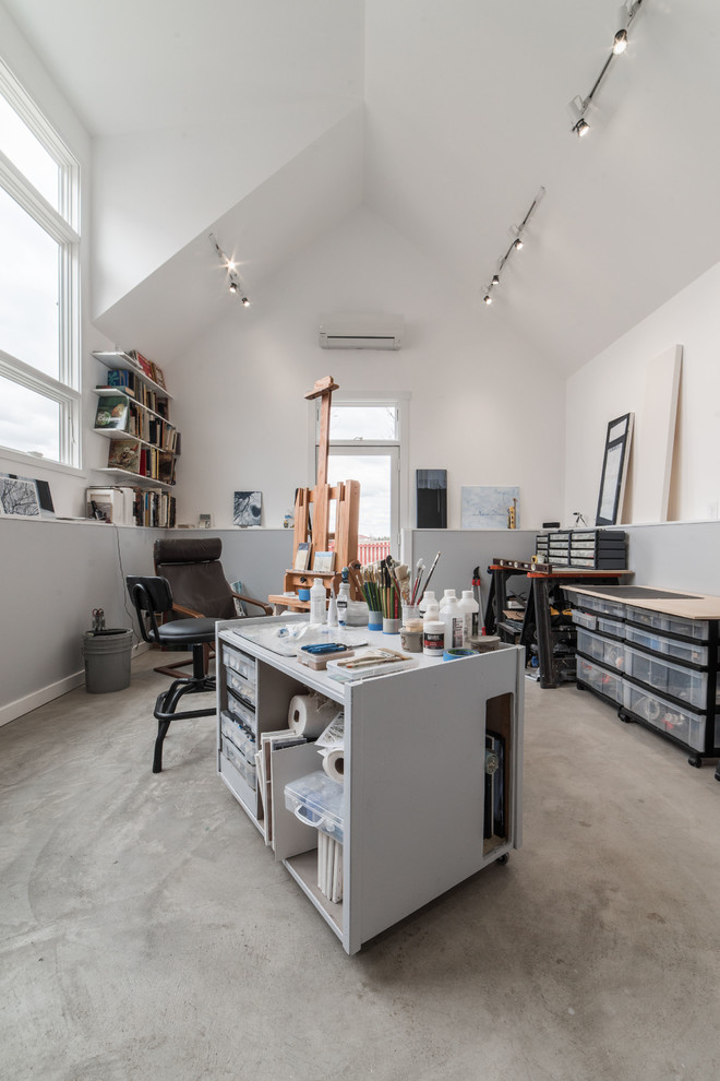 Imagen de sala de manualidades minimalista grande con paredes multicolor, suelo de cemento, escritorio independiente y suelo gris