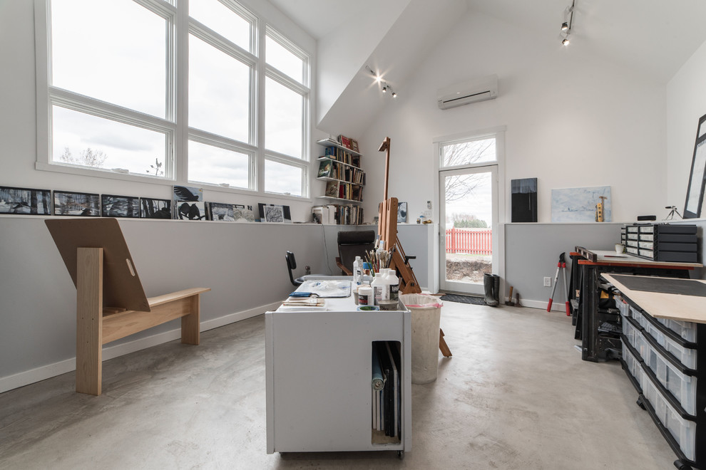 Immagine di una grande stanza da lavoro minimalista con pareti multicolore, pavimento in cemento, scrivania autoportante e pavimento grigio