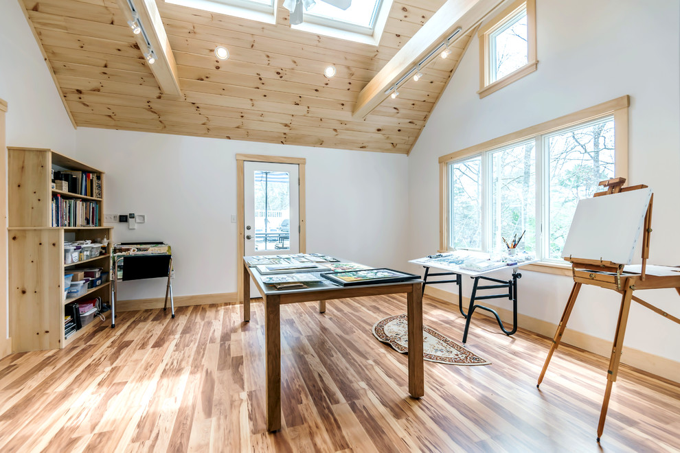 Modelo de estudio minimalista de tamaño medio con paredes blancas, suelo de madera en tonos medios, escritorio independiente y suelo marrón