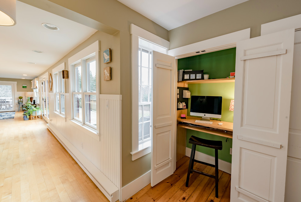 Kleines Landhaus Arbeitszimmer mit grüner Wandfarbe, Einbau-Schreibtisch, braunem Boden, Arbeitsplatz und braunem Holzboden in Boston