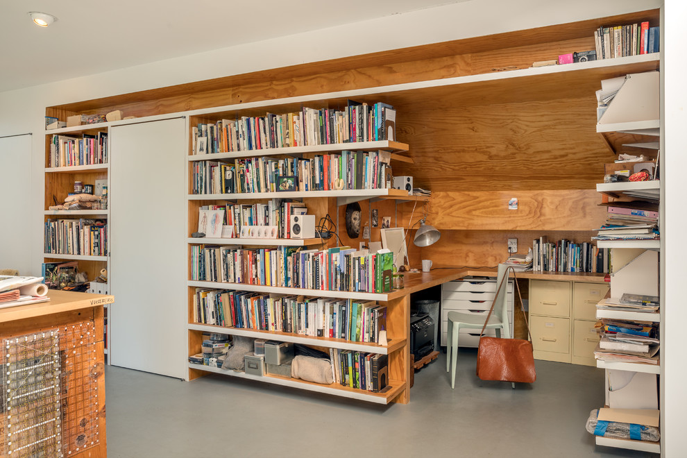 Ejemplo de despacho contemporáneo pequeño con biblioteca, paredes multicolor, escritorio empotrado, suelo gris y suelo de cemento