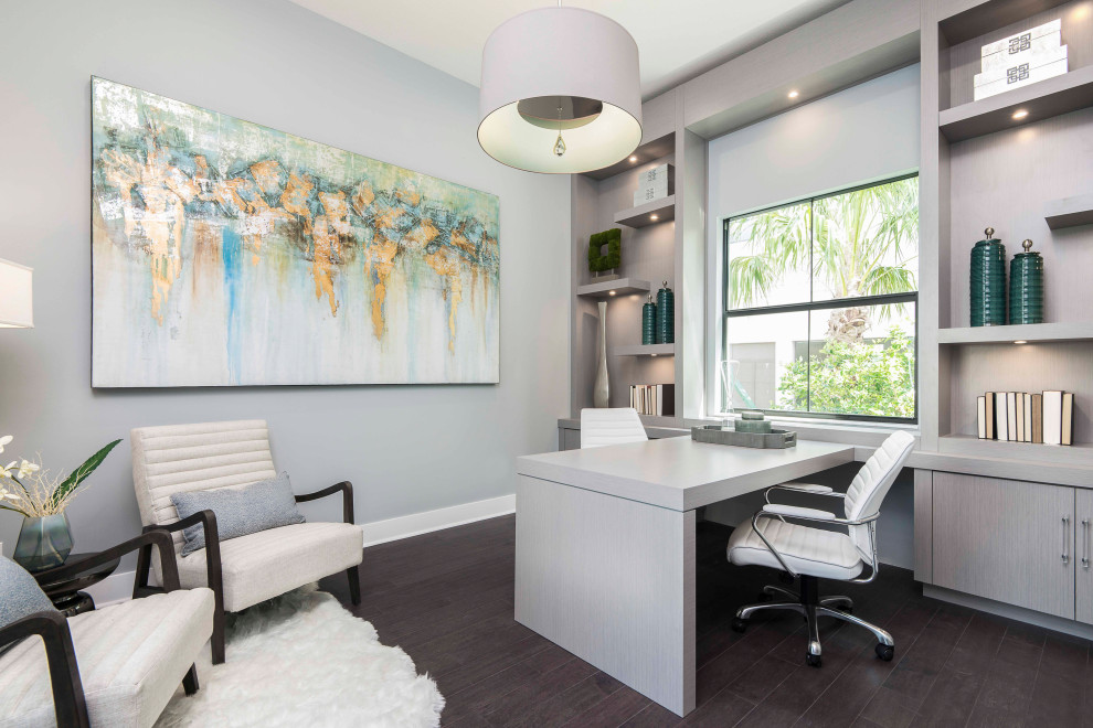 This is an example of a medium sized modern home office in Miami with grey walls, dark hardwood flooring, a built-in desk and brown floors.