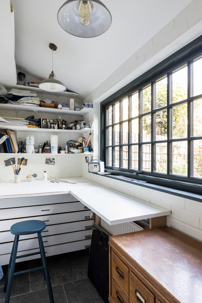 Exempel på ett litet industriellt hobbyrum, med vita väggar, kalkstensgolv, ett inbyggt skrivbord och grått golv