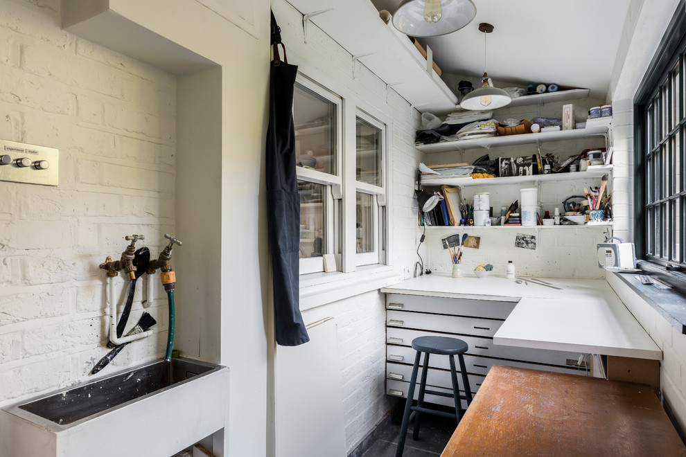 Idéer för ett litet industriellt hobbyrum, med vita väggar, kalkstensgolv, ett inbyggt skrivbord och grått golv