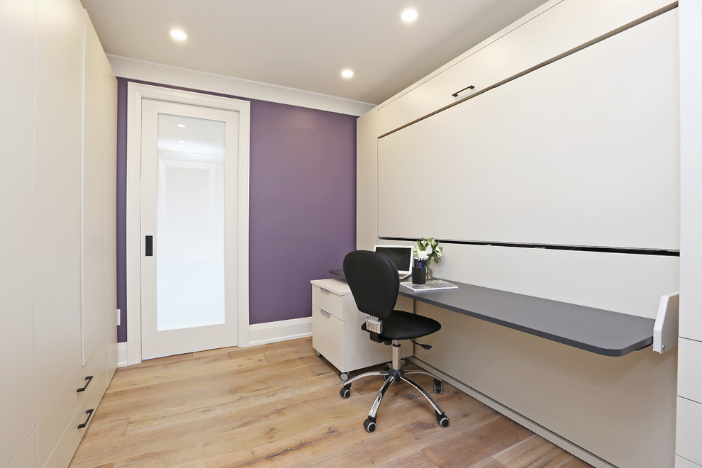 This is an example of a classic home office in Toronto with purple walls, light hardwood flooring, no fireplace and a built-in desk.