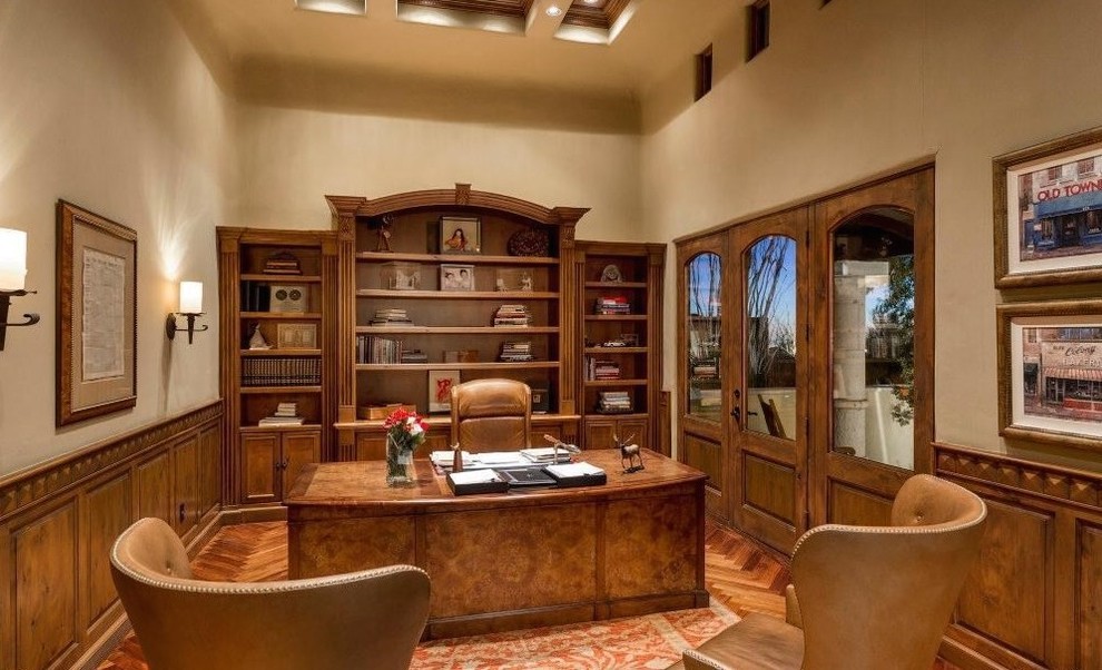 Foto di un ampio ufficio tradizionale con pareti beige, pavimento in legno massello medio, camino classico, cornice del camino in pietra e scrivania autoportante