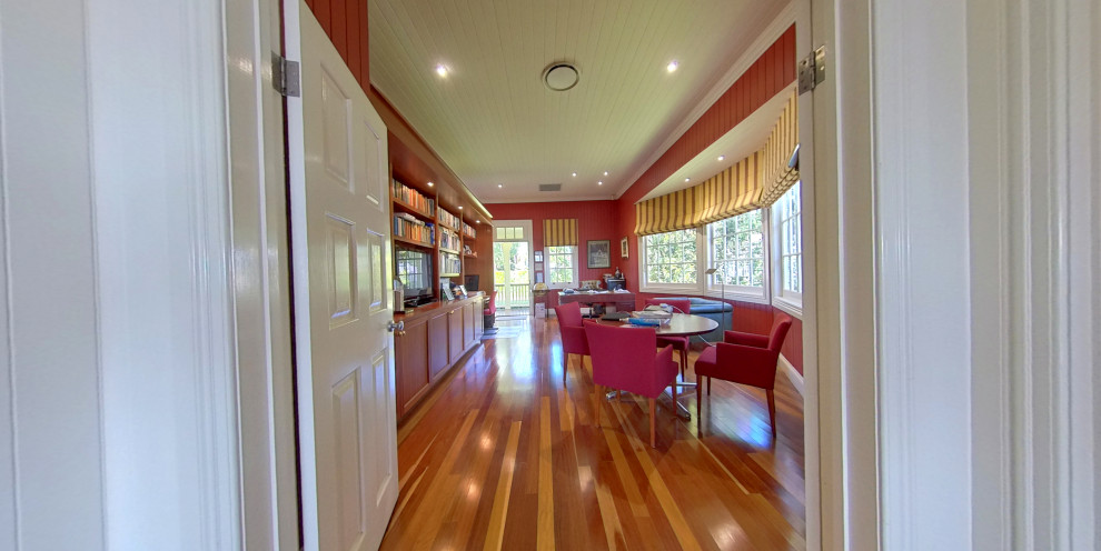 Großes Klassisches Arbeitszimmer mit Arbeitsplatz, roter Wandfarbe, braunem Holzboden, freistehendem Schreibtisch, Holzdecke und Holzwänden in Brisbane