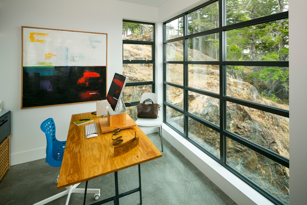 This is an example of a medium sized contemporary study in Vancouver with white walls, concrete flooring, no fireplace and a freestanding desk.