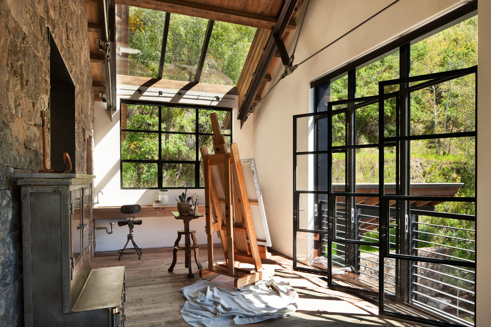 Uriges Arbeitszimmer ohne Kamin mit Studio, weißer Wandfarbe, braunem Holzboden und Einbau-Schreibtisch in Sonstige