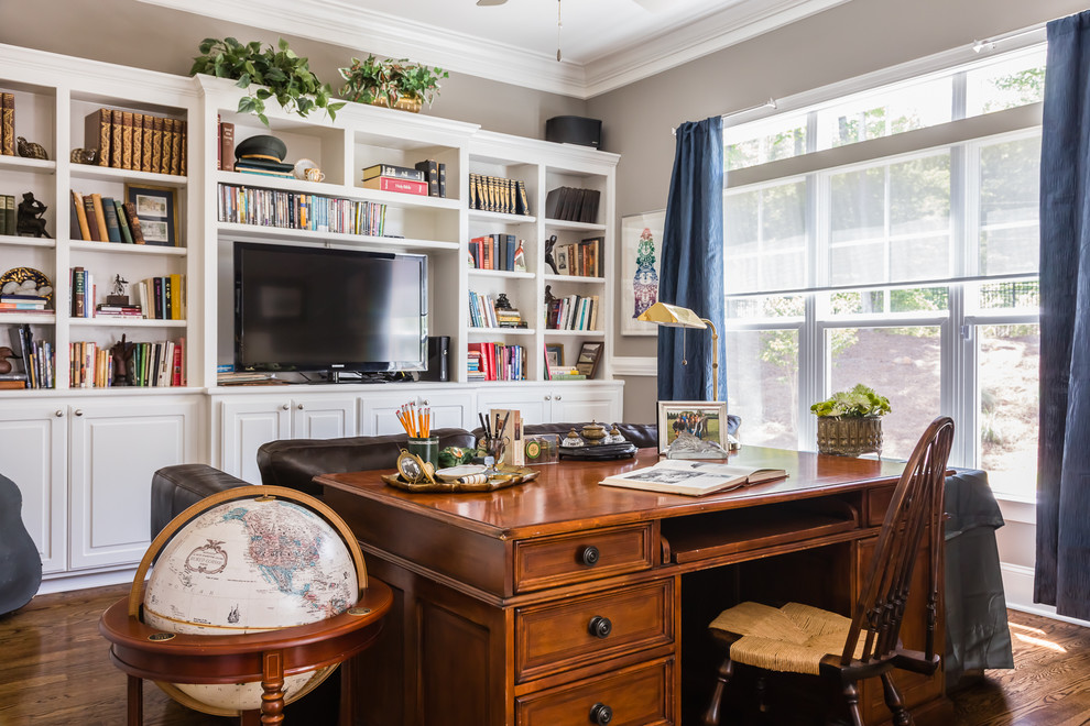 Klassisches Arbeitszimmer mit beiger Wandfarbe, braunem Holzboden und freistehendem Schreibtisch in Raleigh