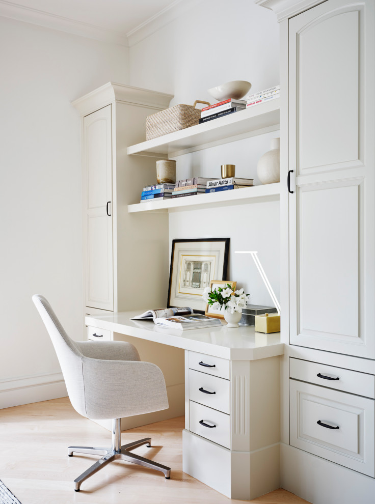 This is an example of a small classic home office in San Francisco with white walls, light hardwood flooring, no fireplace, a built-in desk and brown floors.