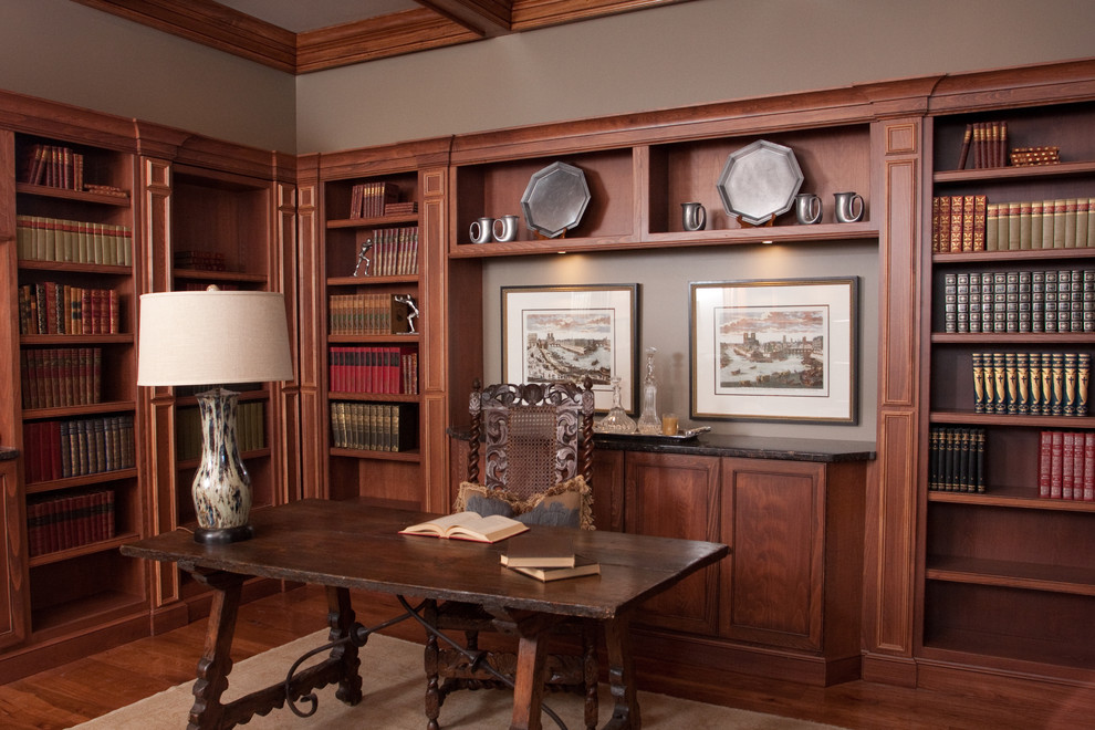 Cette image montre un bureau traditionnel de taille moyenne avec une bibliothèque ou un coin lecture, un mur gris, parquet foncé, aucune cheminée, un bureau indépendant et un sol marron.