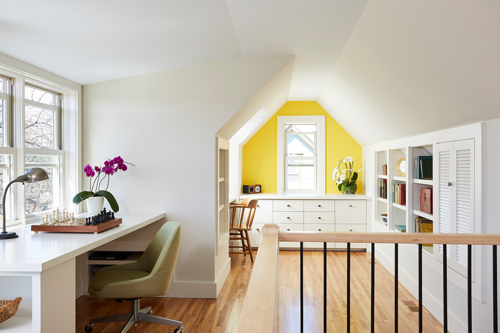 Diseño de despacho tradicional renovado pequeño sin chimenea con paredes amarillas, suelo de madera clara y escritorio empotrado