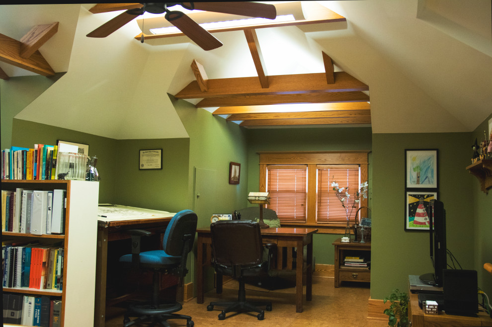 Cette image montre un bureau craftsman de taille moyenne et de type studio avec un mur vert, un sol en liège, un bureau indépendant, un sol marron et un plafond voûté.