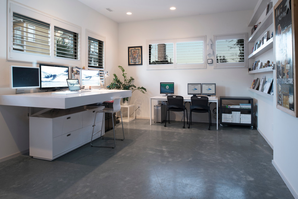 Modelo de despacho actual grande sin chimenea con paredes blancas, escritorio empotrado y suelo gris