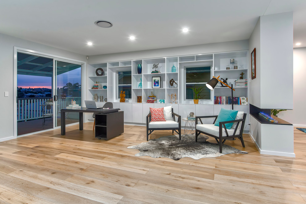 Geräumiges Modernes Arbeitszimmer mit Arbeitsplatz, grauer Wandfarbe, hellem Holzboden, Gaskamin und freistehendem Schreibtisch in Brisbane