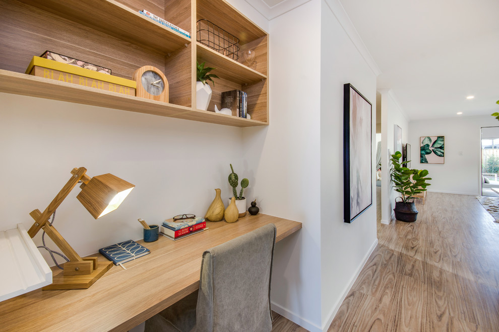 Immagine di un ufficio minimal con pareti bianche, pavimento in laminato e scrivania incassata