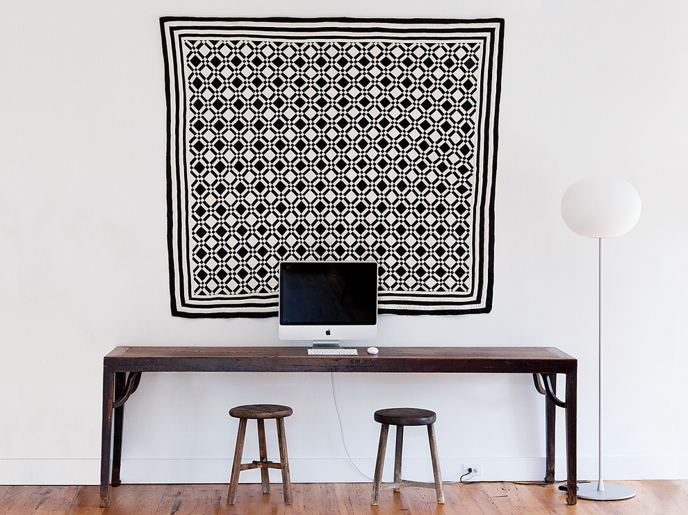 Inredning av ett minimalistiskt arbetsrum, med vita väggar och ett fristående skrivbord