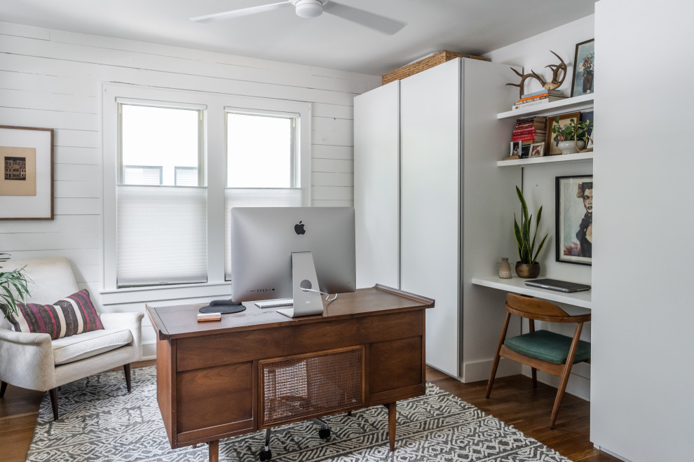 Example of a transitional freestanding desk medium tone wood floor, brown floor and shiplap wall home office design in Austin with white walls