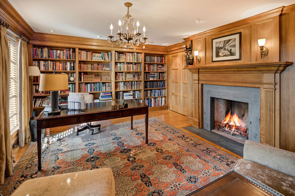 Imagen de despacho clásico con suelo de madera en tonos medios, biblioteca, paredes marrones, todas las chimeneas, escritorio independiente y suelo marrón