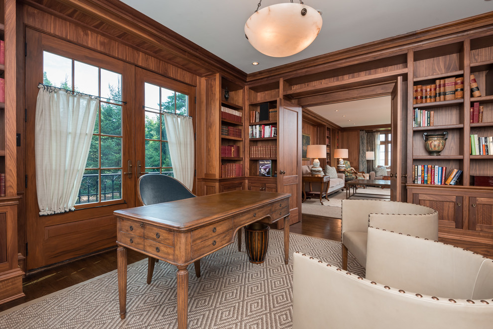 Ejemplo de despacho tradicional renovado grande con biblioteca, paredes marrones, suelo de madera oscura, escritorio independiente y suelo marrón