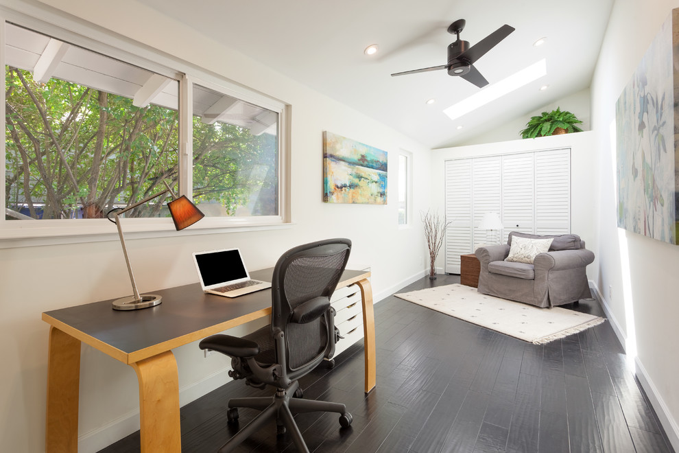 Imagen de despacho actual con paredes blancas, suelo de madera oscura y escritorio independiente