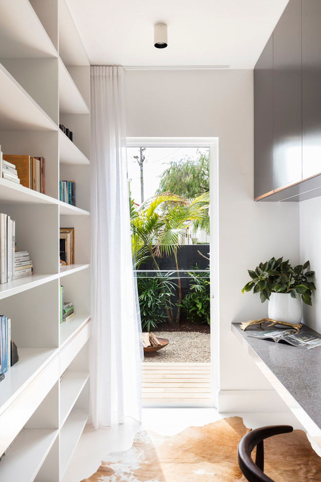 Идея дизайна: маленький домашняя библиотека в современном стиле с белыми стенами, встроенным рабочим столом и белым полом для на участке и в саду