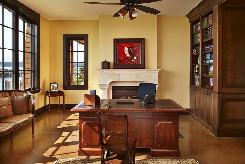シアトルにある広いトラディショナルスタイルのおしゃれなホームオフィス・書斎 (黄色い壁、標準型暖炉、石材の暖炉まわり、自立型机) の写真
