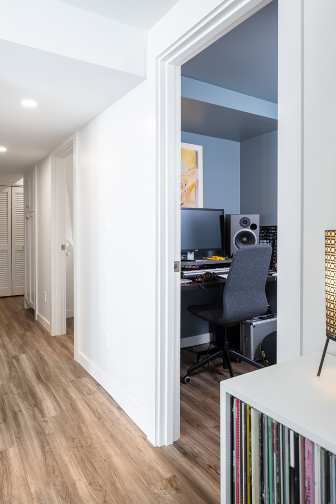 Idee per un piccolo atelier minimalista con pareti bianche, pavimento in vinile, scrivania autoportante e pavimento marrone