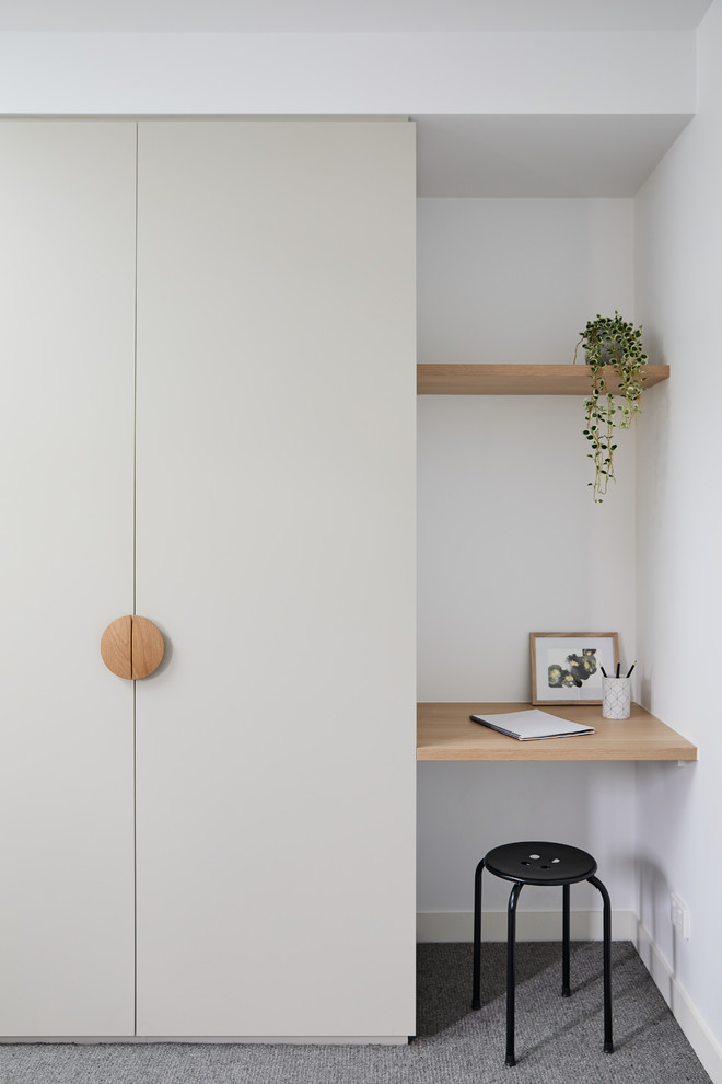 Réalisation d'un petit bureau nordique avec un mur blanc, moquette, un bureau intégré et un sol gris.